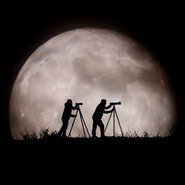 Dos fotógrafos en silueta delante de la Luna, fotografía de Chechu Senís