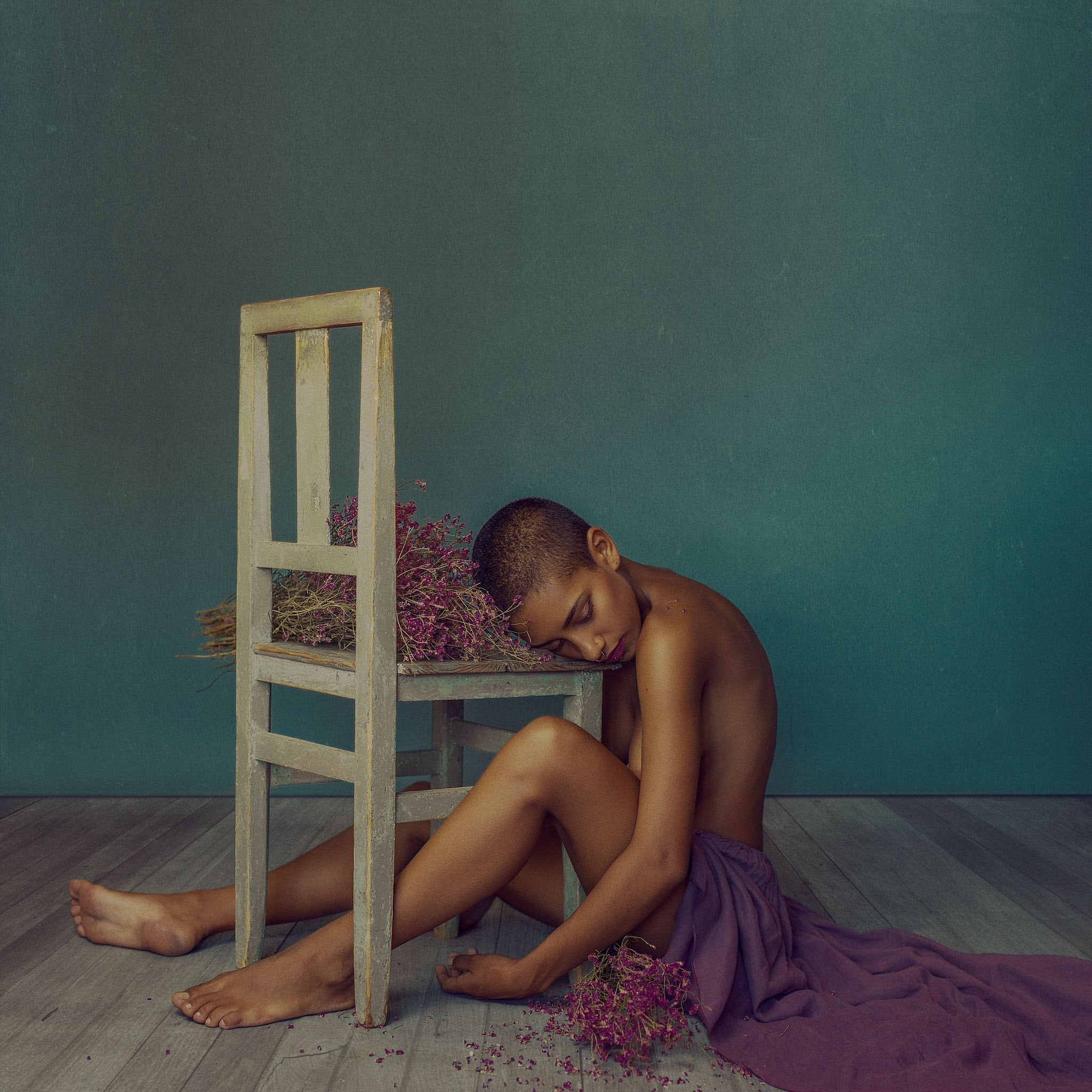 Fotografía conceptual de Mara Saiz: figura sentada junto a una silla sobre fondo verde