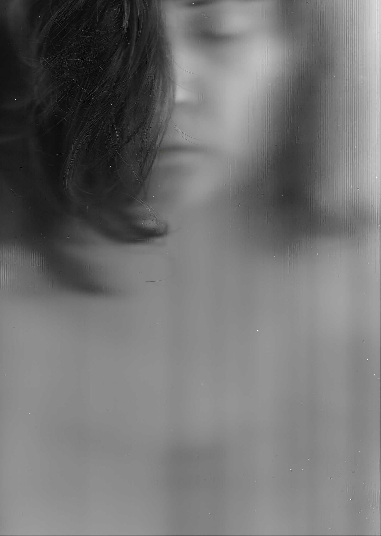 Retrato analógico en blanco y negro con una figura desenfocada tras un cristal
