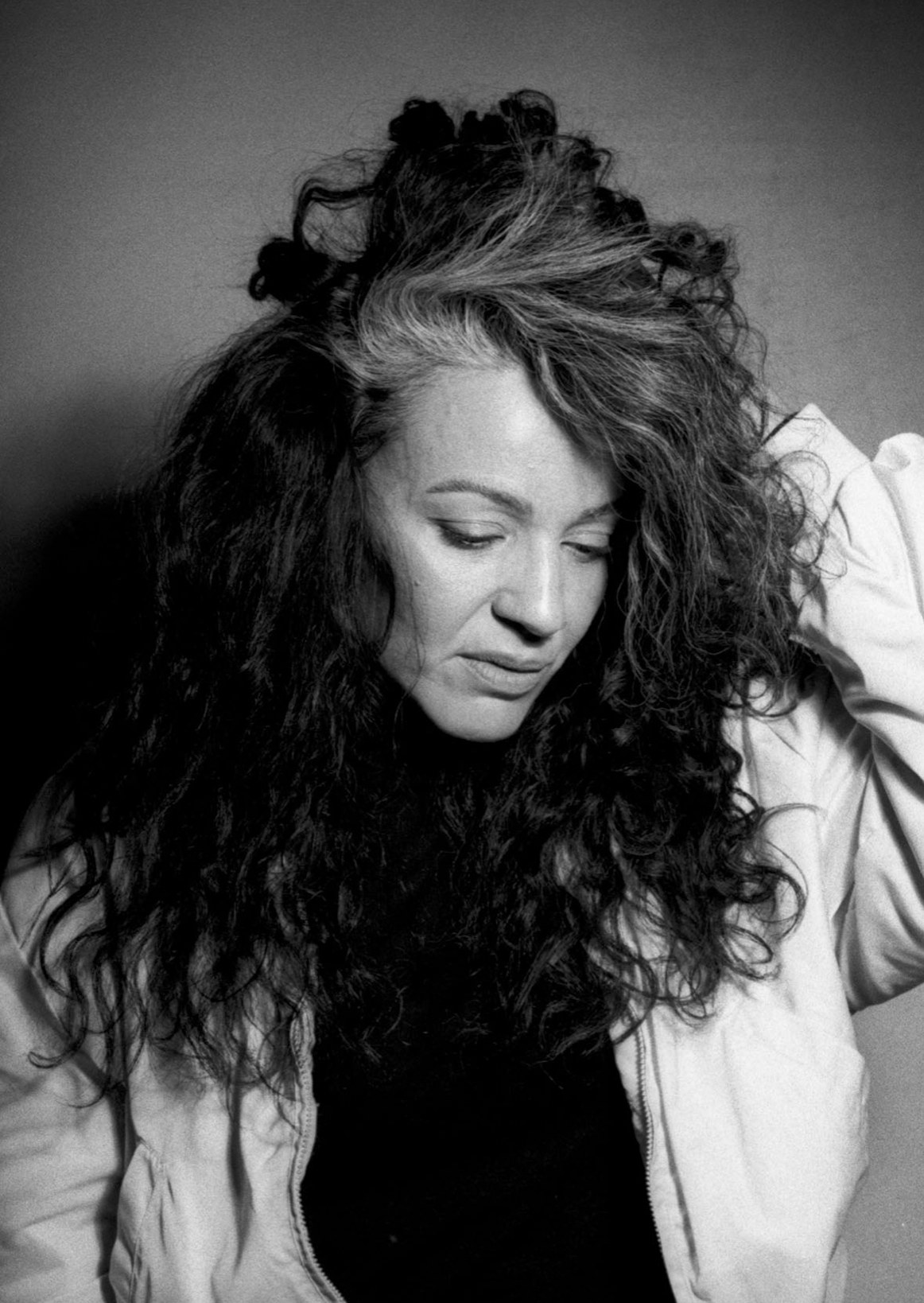 Retrato en blanco y negro de una mujer de cabello rizado mirando hacia abajo