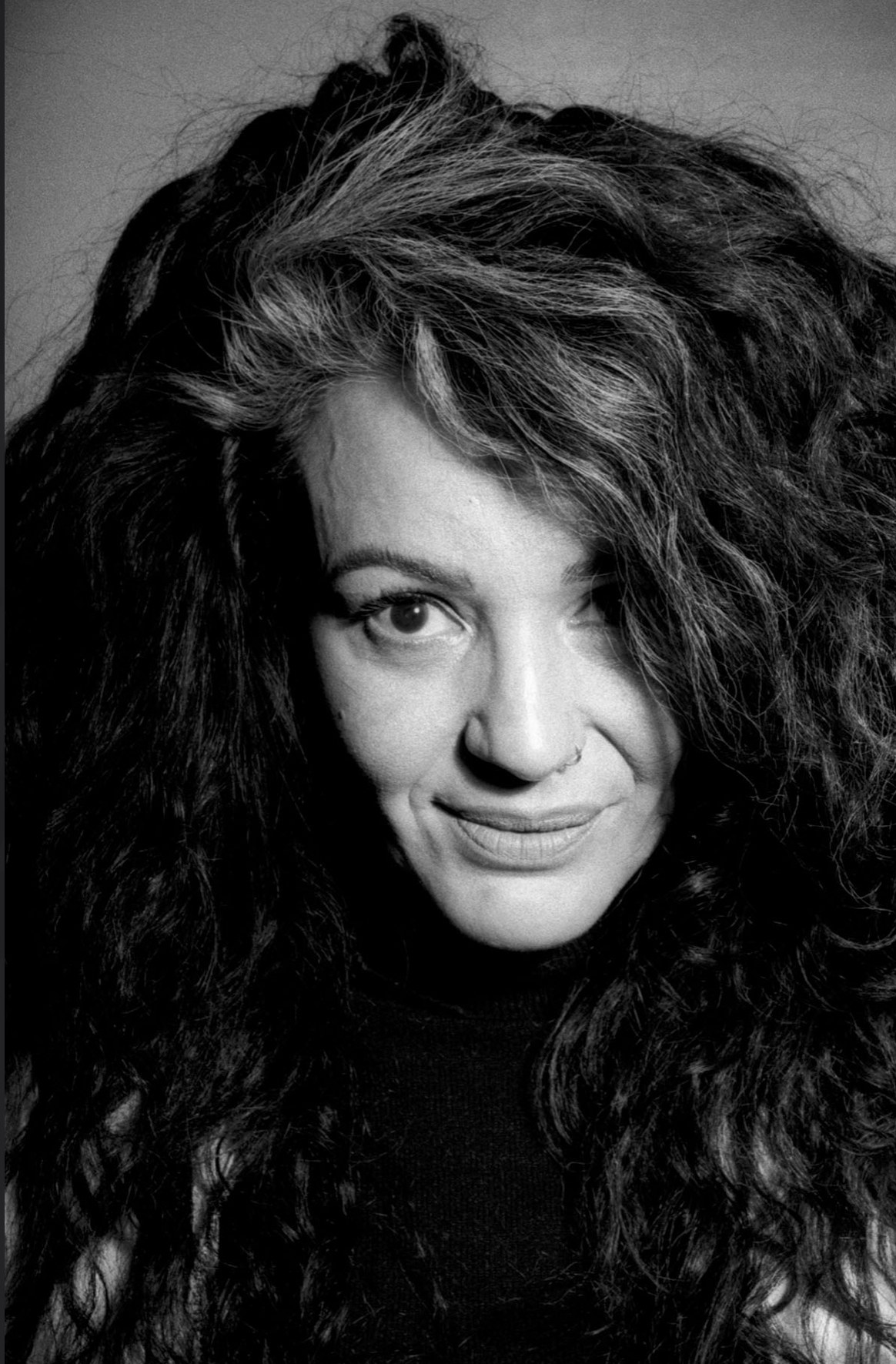 Retrato en blanco y negro de una mujer de cabello rizado mirando a cámara