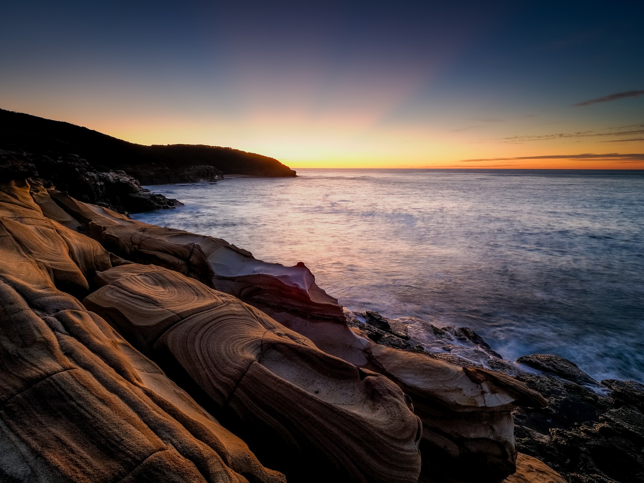 Costa rocosa iluminada por los últimos colores del atardecer
