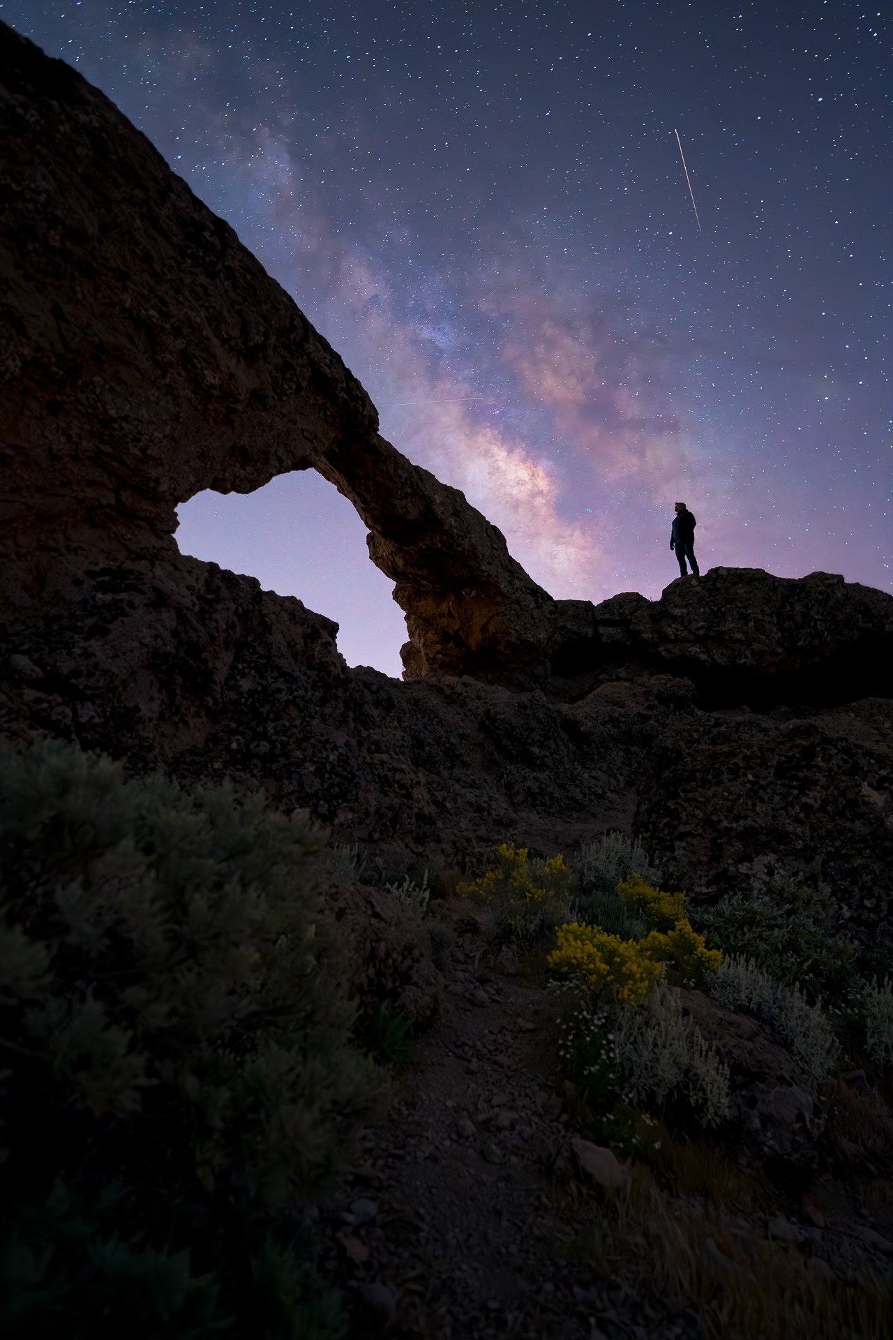 Figura sobre un arco rocoso bajo la Vía Láctea, fotografía de David Rodríguez