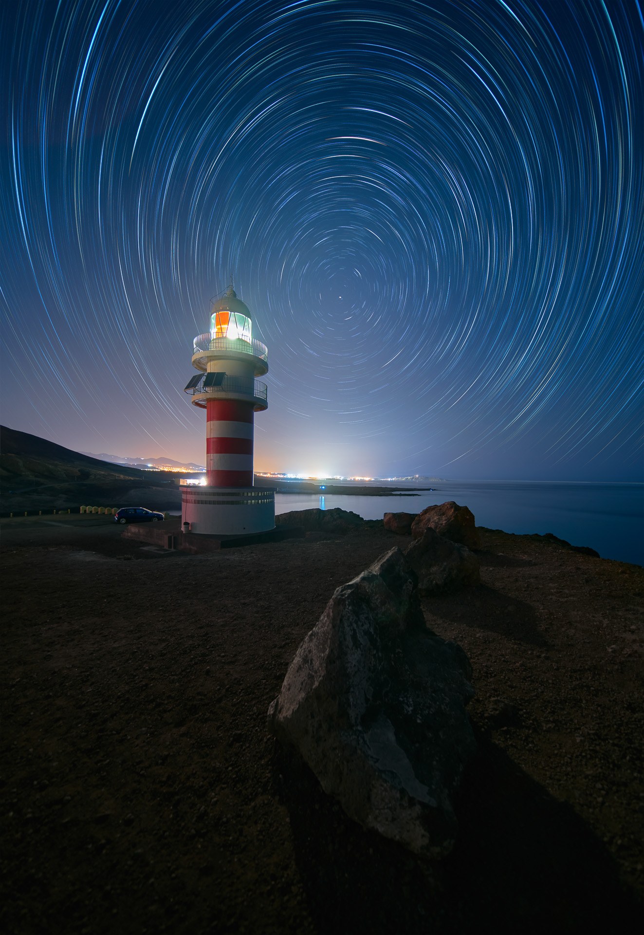 Faro entre rocas bajo trazas estelares, fotografía de David Rodríguez